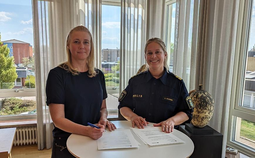 Kommunalråd Anna Andresen och lokapolischef Anna Nilsson står vid ett bord med varsin penna i handen och ska skriva under medborgarlöftet som ligger på bordet.